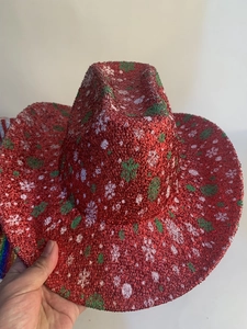 Detail of red Christmas cowboy hat with sparkling sequins and festive green snowflake patterns