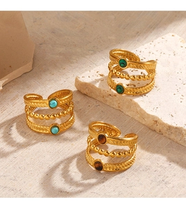 Détail de bagues bohèmes dorées avec turquoise et malachite sur une pierre texturée