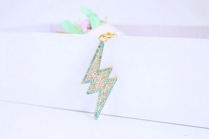 Macro shot of gold alloy lightning bolt charm with sparkling blue and clear rhinestones