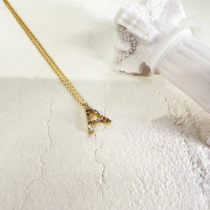 Detailed view of an 18k gold letter A pendant necklace with colorful cubic zirconia