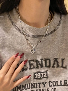 Detail of gothic silver heart necklace with cross pendant and multi-color gems