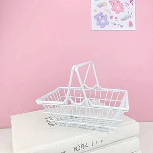 Close-up of a white mini iron mesh storage basket with handles on a pink background