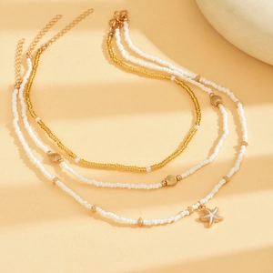 Three-layer beach necklace set with gold beads, seashells and starfish pendant on beige