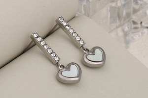 Macro detail of silver drop earrings with heart pendant and sparkling pavé crystals