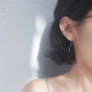 Minimalist silver heart stud earrings with wavy tassel drop shown on a model