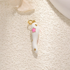 Macro shot of white enamel chili pendant with gold accents and pink star detail