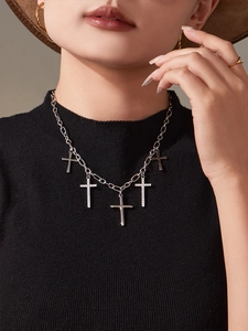 Détail d'un collier argenté avec plusieurs pendentifs en croix et strass sur modèle