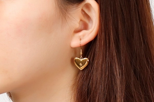 Close-up of elegant gold heart-shaped dangle earrings with crystal on a female model