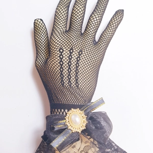 Detail of a black mesh Lolita glove featuring a ribbon bow with a pearl gold brooch