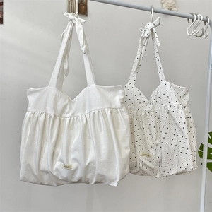 Detail of white and polka dot canvas tote bags with pleated fabric and bow shoulder straps