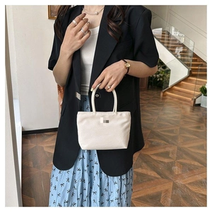 Photo lifestyle d'un sac seau blanc en nylon porté avec une jupe à fleurs et un blazer