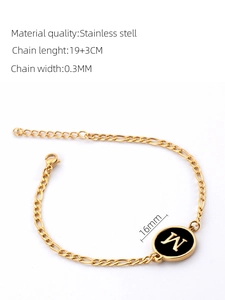 Detail of 18K gold Figaro chain bracelet with black shell pendant featuring letter W