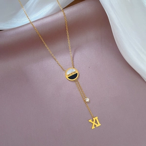 Macro view of shell tassel pendant with Roman numeral engraving on a gold titanium necklace