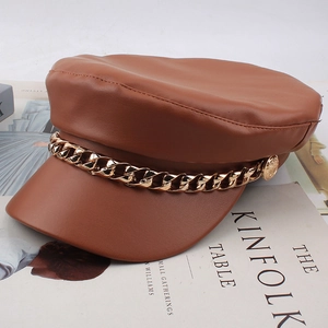 Detailed macro view of the brown faux leather beret featuring a thick gold chain link