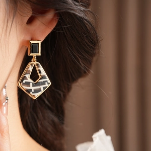 Close-up of zebra print diamond-set geometric resin drop earrings on a female model