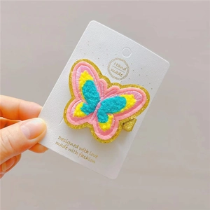 Close-up of handmade embroidered butterfly hair clip with colorful floral details on card
