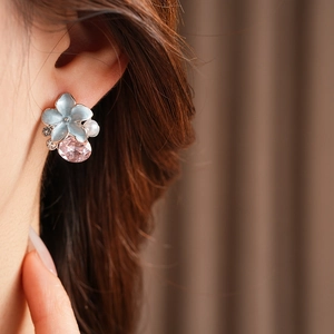 Détail macro d'une boucle d'oreille fleurie vintage avec émail bleu et cristaux