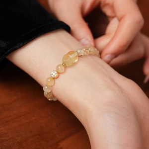 Close-up of golden beaded rutilated quartz bracelet with PiXiu charm and coin pendant