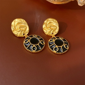 Detail of vintage gold and black enamel round earrings on a brown leather surface