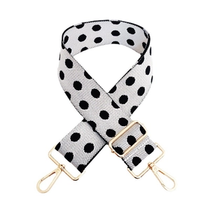 Close-up of adjustable wide woven shoulder strap with black and white polka dots and gold hardware