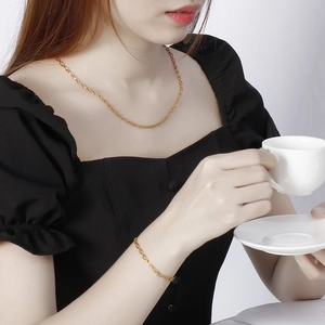 Elegant gold-plated geometric chain necklace and bracelet set worn by a model