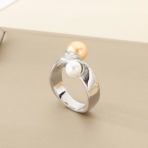 Close-up of geometric stainless steel ring featuring dual pearl inlay in champagne and white