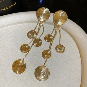 Detailed macro of gold layered round discs earrings with sunburst texture and tassels
