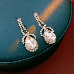 Macro shot of silver teardrop earrings featuring pear-cut crystals on a dark surface