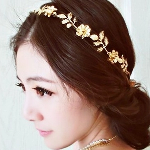 Detailansicht eines goldenen Haarreifs mit Blatt und Blume am Kopf eines Models