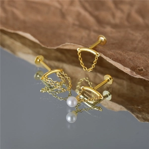 Detail of S925 silver gold tassel chain earrings with pearl on a mirrored surface