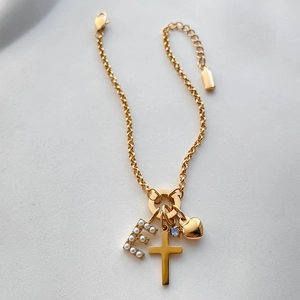 Bracciale in acciaio dorato con ciondoli a croce, lettera E di perle e cuore.