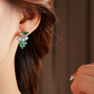 Close-up of elegant grape cluster earrings with green and blue zircon stones on a model