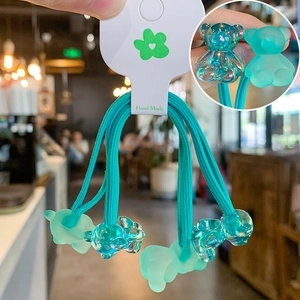 Detail of four teal gummy bear hair ties with matte and transparent textures on cards