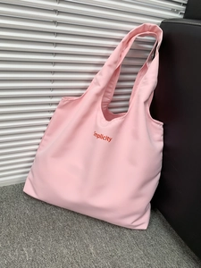Detailed texture of pink canvas tote bag featuring red Simplicity embroidery stitching