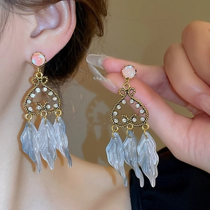 Détail de boucles d'oreilles dorées vintage avec gemmes roses et feuilles bleues