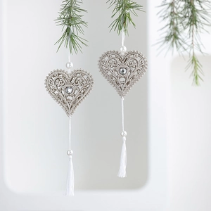 Silver glitter hollow heart ornament with white pearl and tassel on Christmas pine branch