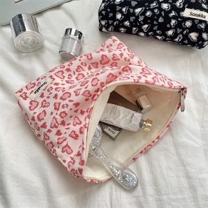 Macro shot of large pink heart leopard corduroy pouch with zipper and cosmetic items