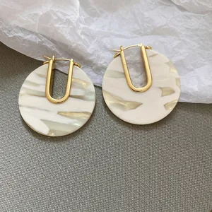 Détail de boucles d'oreilles en U plaquées or 18k avec anneaux en résine blanche