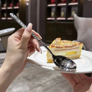 Close-up of a long-handle stainless steel soup spoon with marble pattern during tea time