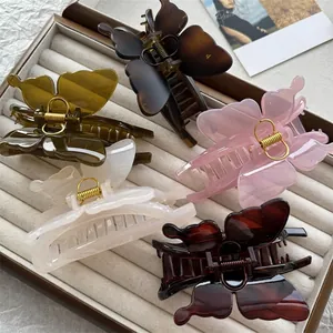 Five butterfly hair claws in translucent acetate colors displayed on gray velvet tray