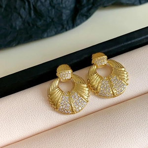 Detailed view of gold circular fan earrings with sparkling rhinestones on leather padding