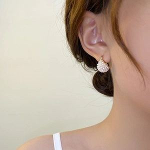 Close-up of fan-shaped gold pearl earrings on a model showing elegant vintage texture