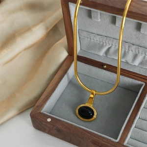 Vintage oval black stone pendant necklace with gold plated snake chain on display