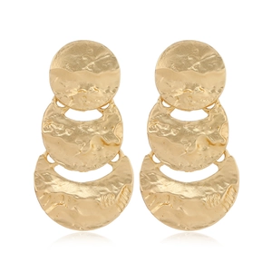 Close-up of golden matte earrings with layered hammered texture and crescent shape design