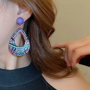 Close-up of geometric pattern drip oil acrylic drop earrings worn by a model