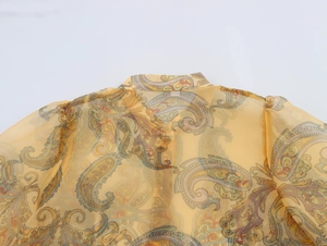 Detail of yellow paisley organza blouse showing sheer fabric texture and lantern sleeve pleats