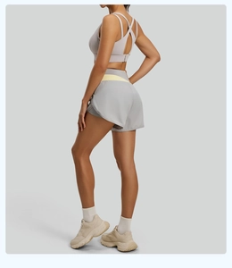 Détail du soutien-gorge de sport gris à bretelles croisées et du short avec ceinture jaune