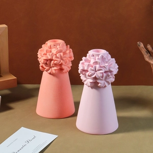 Detail view of coral and pink flower-embossed candle holder vases on a wooden setting