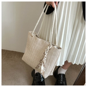 Détail du sac cabas en paille beige avec anses en corde et foulard en soie imprimé chic
