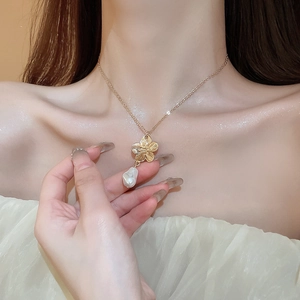 Elegant gold flower necklace with white baroque pearl drop worn by female model